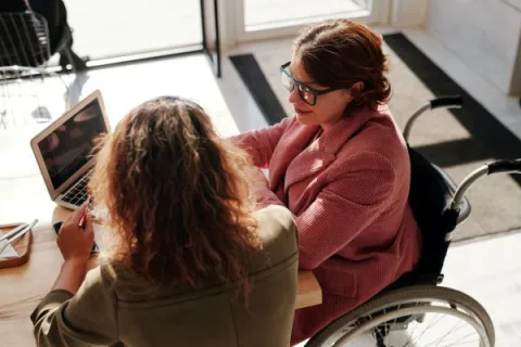 Woman wheelchair user meeting with woman at desk